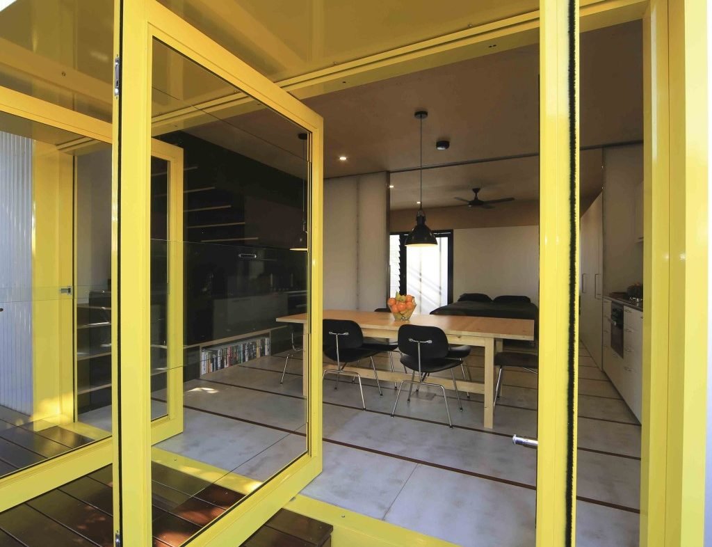 The entrance door to the dining area of a bright yellow 'pavilion' style house.
