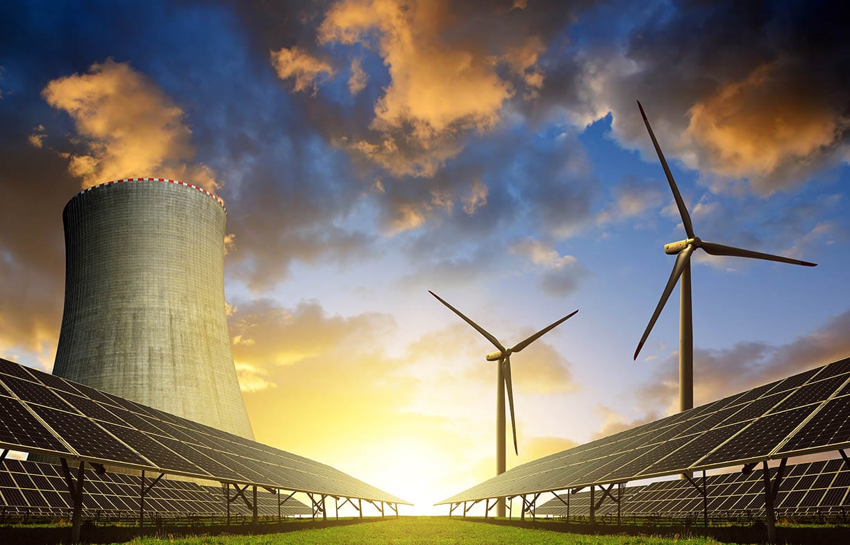 Solar energy panels before a nuclear power plant and wind turbines at sunset